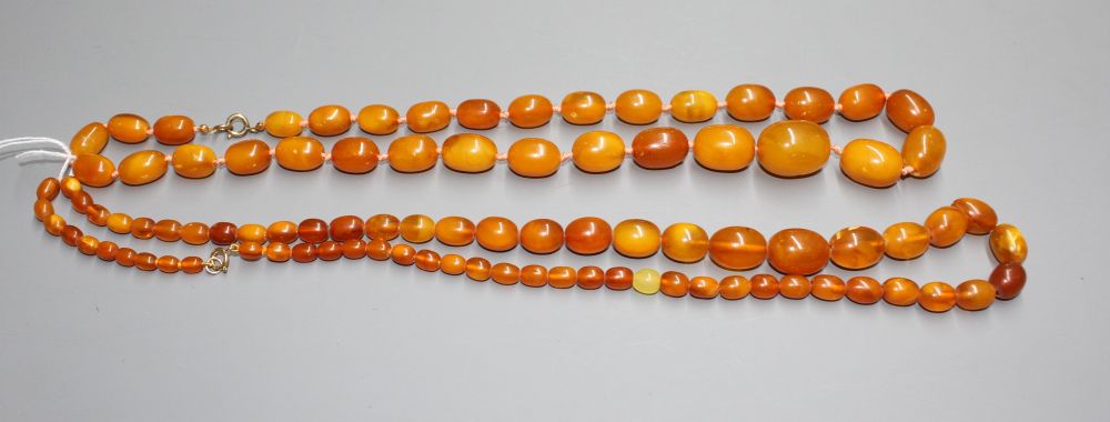 Two single strand graduated oval amber bead necklaces, with yellow metal clasps, one stamped 375,